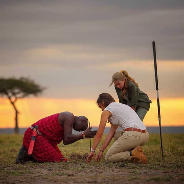 Maasai community elder in traditional dress with Masai Mara landscape behind